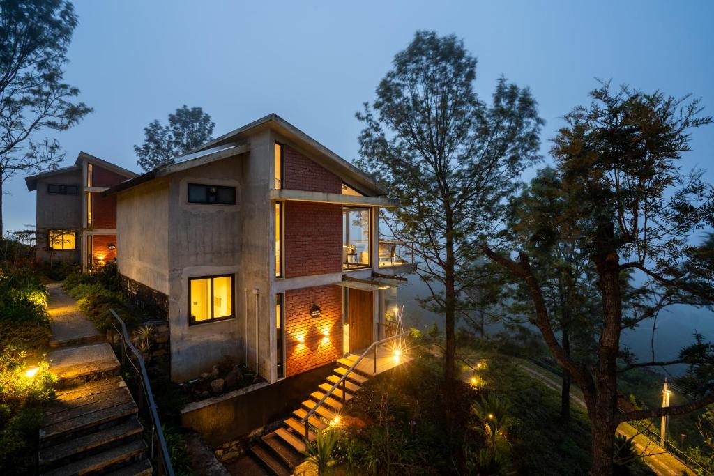 ein Haus im Wald bei Nacht mit Lichtern in der Unterkunft LohonoStays Amani Villa 11B in Coonoor