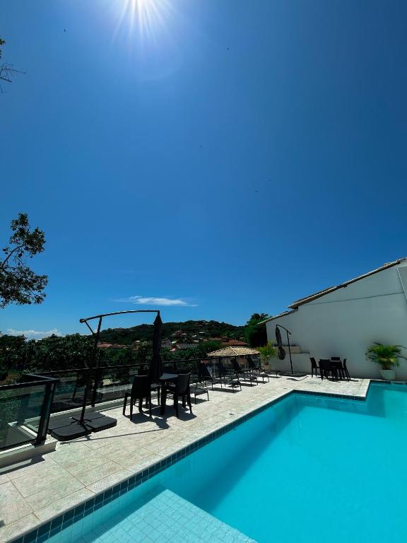a swimming pool with tables and chairs on a building at La bardot boutique Pousada in Búzios