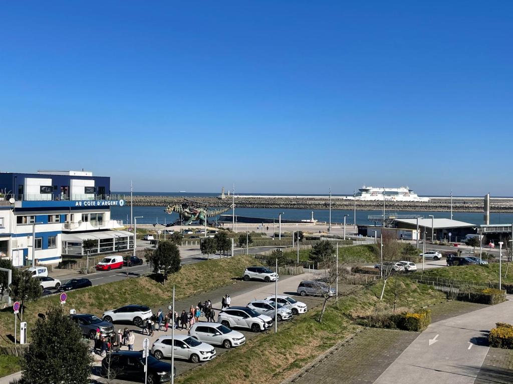 a parking lot with cars parked in front of a harbor at Studio Horizon Bleu, vue mer in Calais