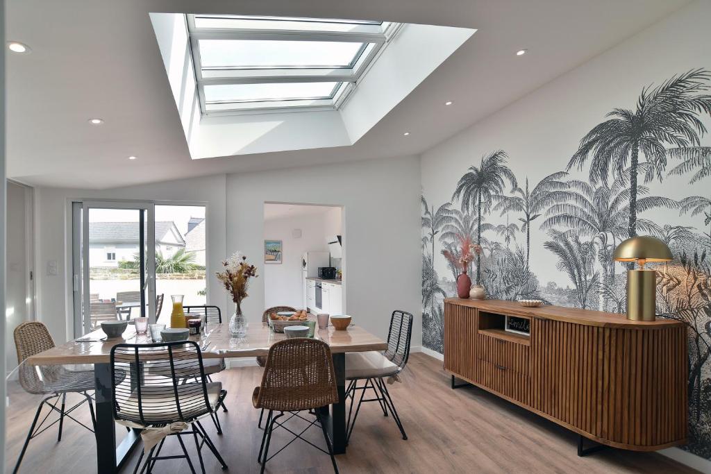 une salle à manger avec une table, des chaises et une fresque murale représentant des palmiers dans l'établissement La Tranquilla - A quelques pas de la plage, à Saint-Cast-le-Guildo