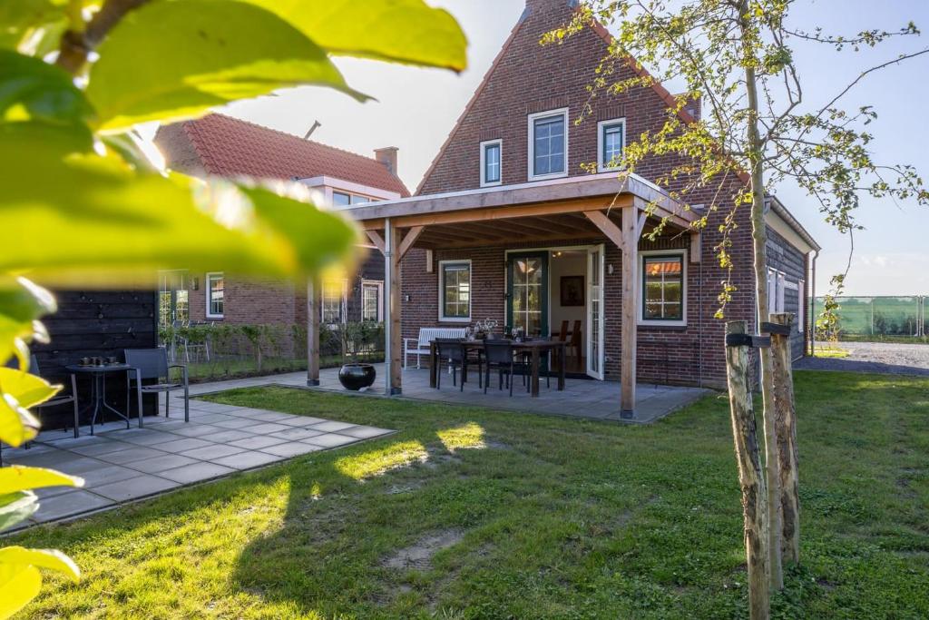 a brick house with a covered patio with a table at Hello Zeeland - Vakantiewoning Knuitershoek 104 in Kloosterzande