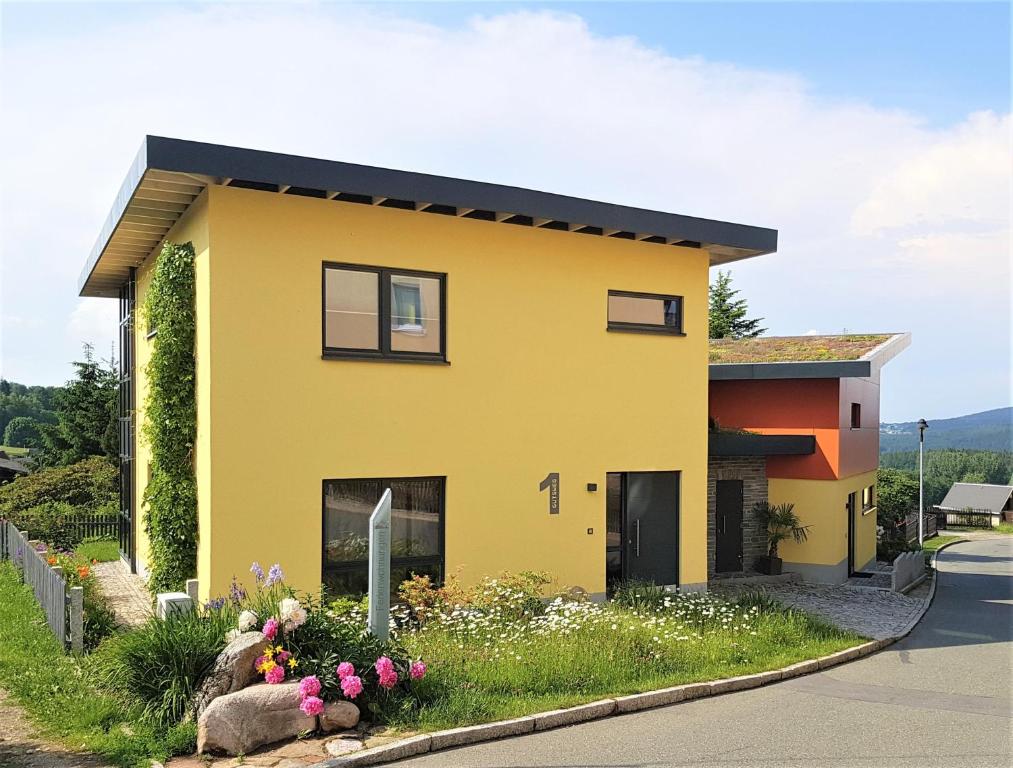 a yellow house with some flowers in front of it at Moderne, Niveauvoll Eingerichtete Ferienwohnung in Eibenstock