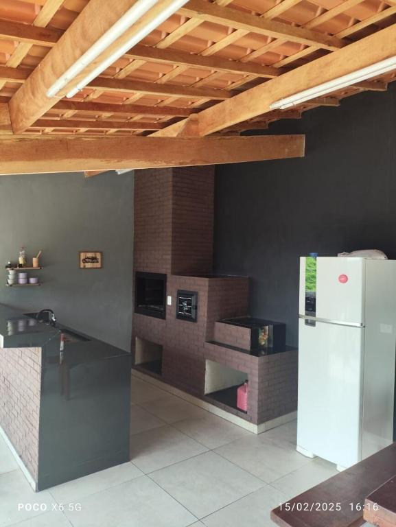 a kitchen with a white refrigerator under a wooden ceiling at Chácara Morada do Sol Ibiúna in Ibiúna