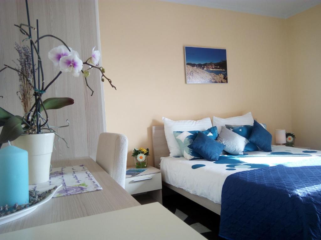 um quarto com uma cama azul e uma mesa com uma mesa de sidx em Marina Guesthouse em Korčula
