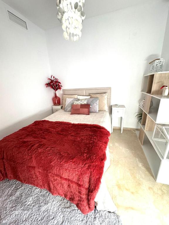 Un dormitorio con una cama con una manta roja. en Sevilla tu casa, en Espartinas