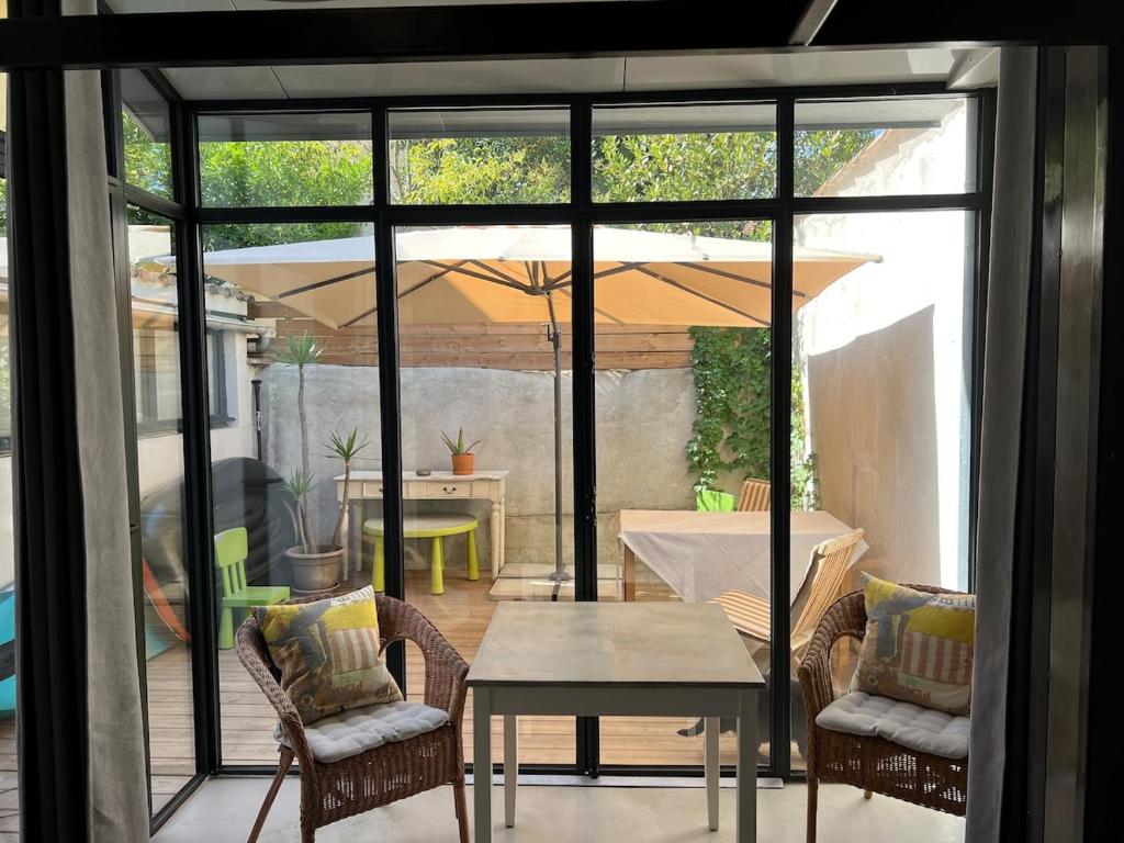 un patio avec une table, des chaises et un parasol dans l'établissement Folie sur Cour à Palavas-les-Flots 3 etoiles, à Palavas-les-Flots