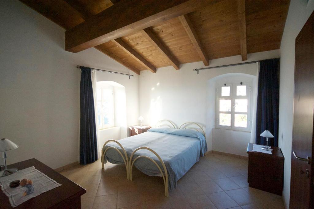 ein Schlafzimmer mit einem Bett, einem Tisch und zwei Fenstern in der Unterkunft Al Vecchio Convento Mare e Monti in Ortonovo
