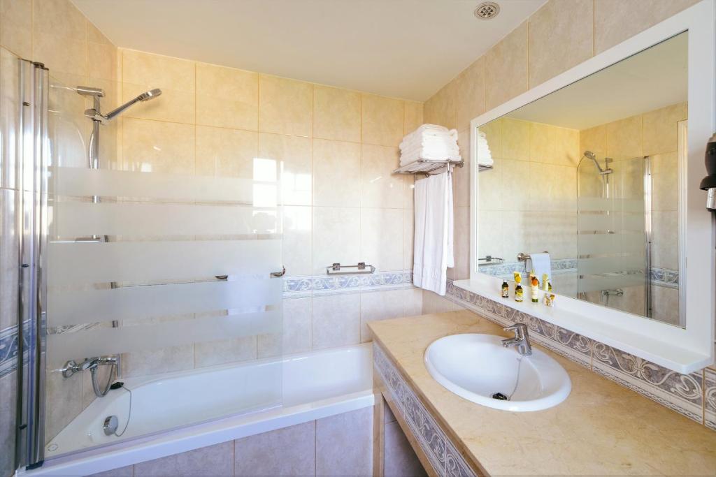 W łazience znajduje się umywalka, wanna i lustro. w obiekcie Club Vista Serena w mieście Maspalomas