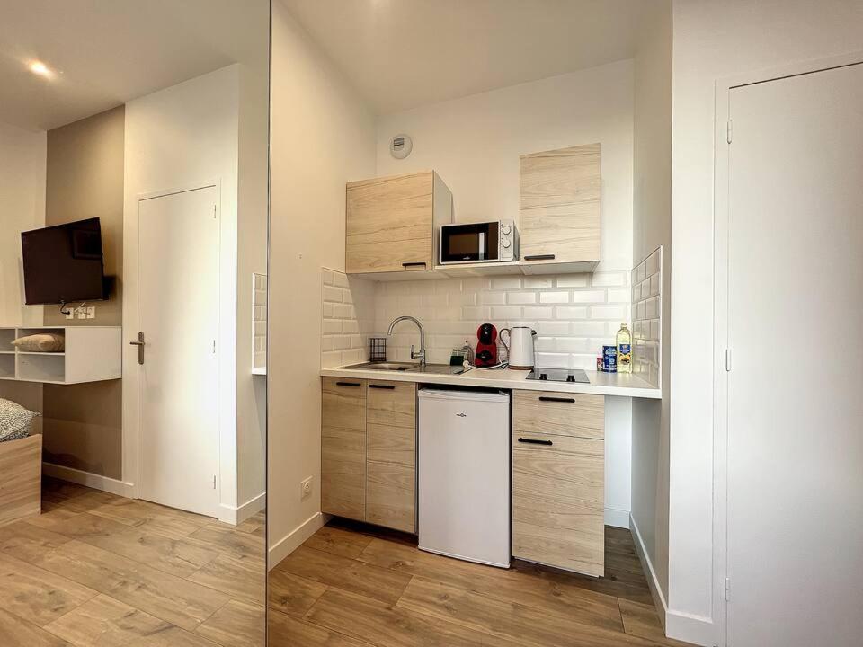 une cuisine avec des armoires blanches et un réfrigérateur blanc dans l'établissement Le Saint Michel - Studio proche gare, à Saint-Brieuc