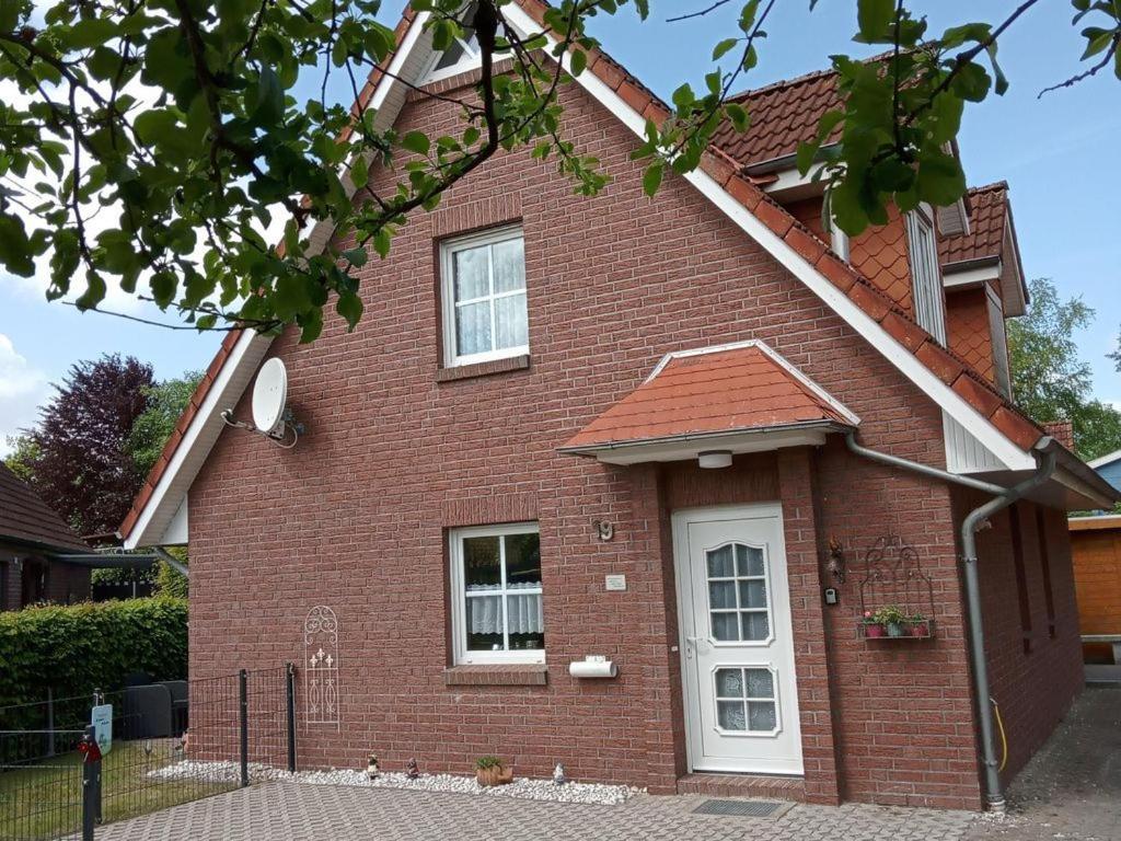 a red brick house with a white door at Ferienhaus Seesternchen Aurich-Tannenhausen in Aurich