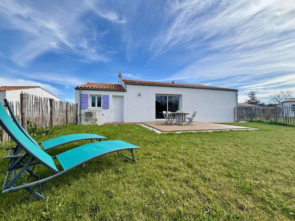 a blue chair sitting in the grass in front of a house at Maison neuve 3 pièces calme sur Oléron proche plage et commerces - FR-1-246A-298 in Dolus d'Oléron