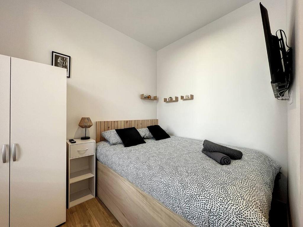 une chambre avec un lit et un mur blanc dans l'établissement Studio la Ville Jouha - proche gare, à Saint-Brieuc