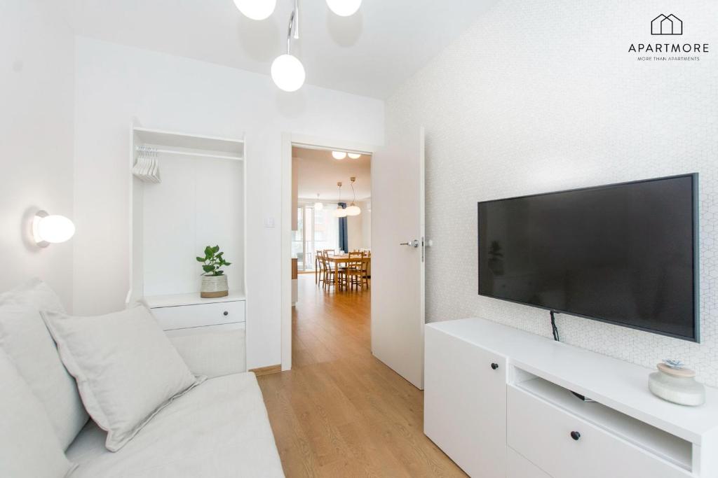 Small living area with wall-mounted TV, white storage cabinet, light sofa and open doorway to dining.