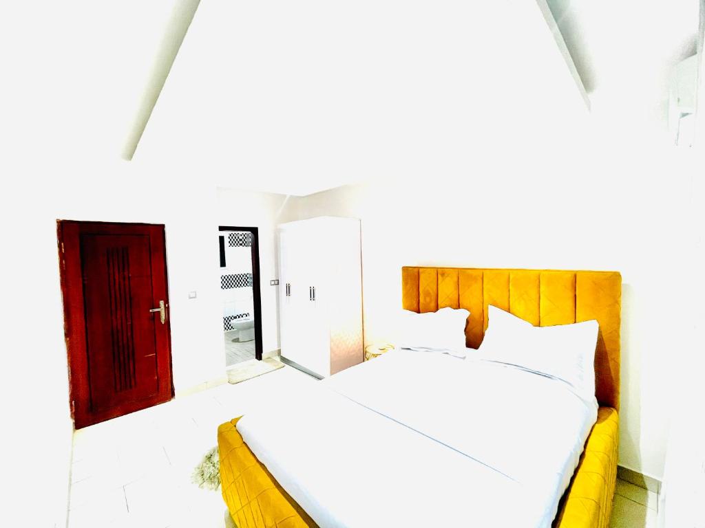 ein Schlafzimmer mit einem weißen Bett und einer roten Tür in der Unterkunft Mich appart in Jaunde