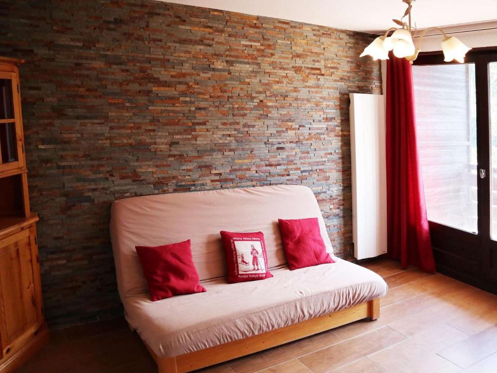- un canapé blanc avec des oreillers rouges sur un mur en briques dans l'établissement Appartement rénové 6 pers, au pied des pistes - FR-1-322-159, aux Orres