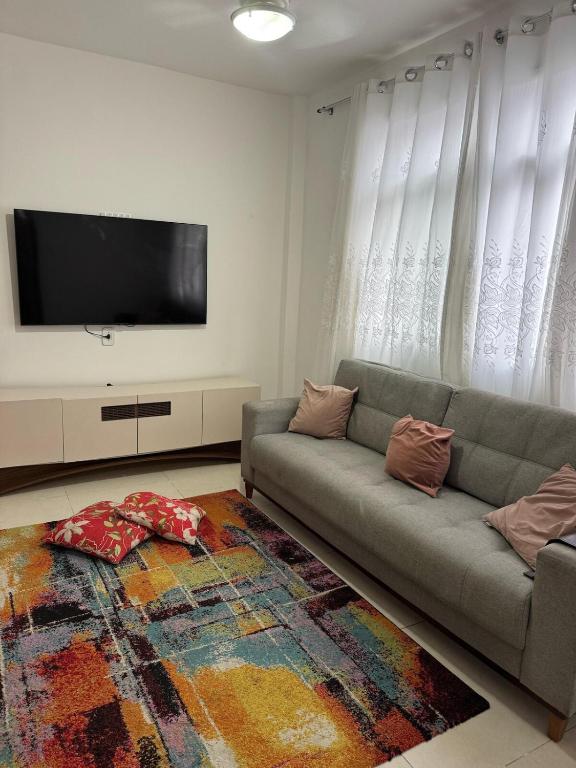 a living room with a couch and a flat screen tv at Itapuã - 4 Minutos da Praia - Quarto com Suíte in Vila Velha