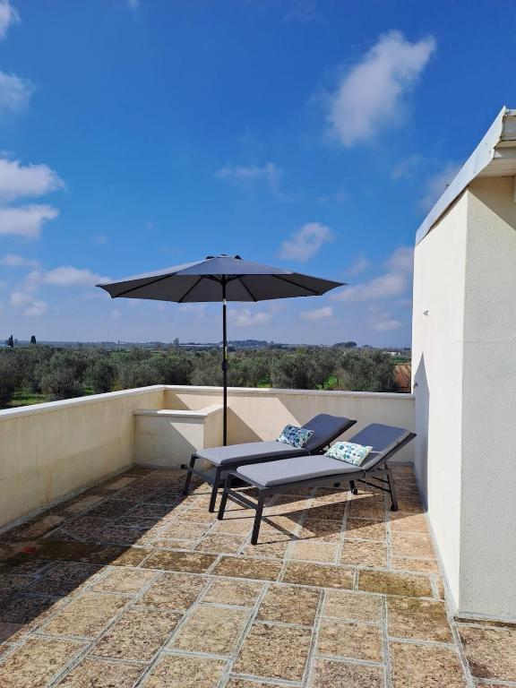 eine Terrasse mit Sonnenschirm und Bank auf einem Dach in der Unterkunft CasaAmena in Nardò