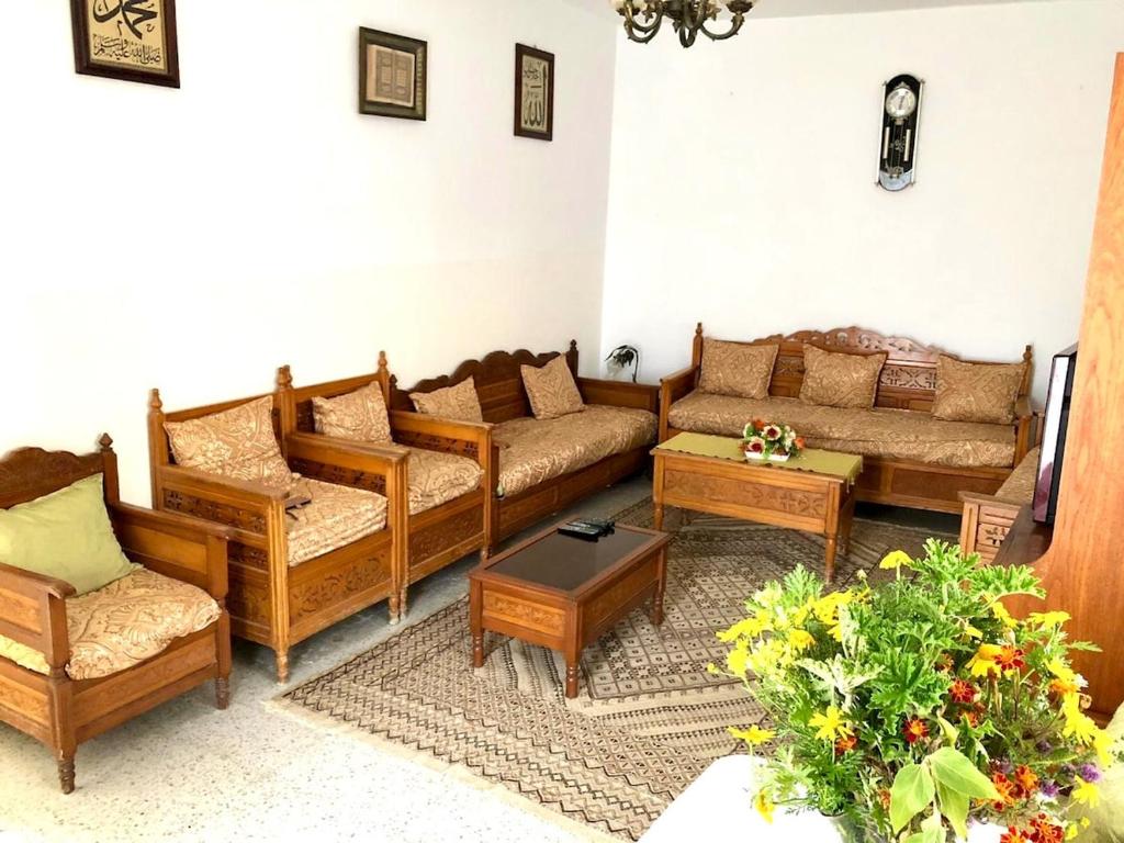 a living room with couches and tables and flowers at Maison Tunisienne avec Patio in Sousse