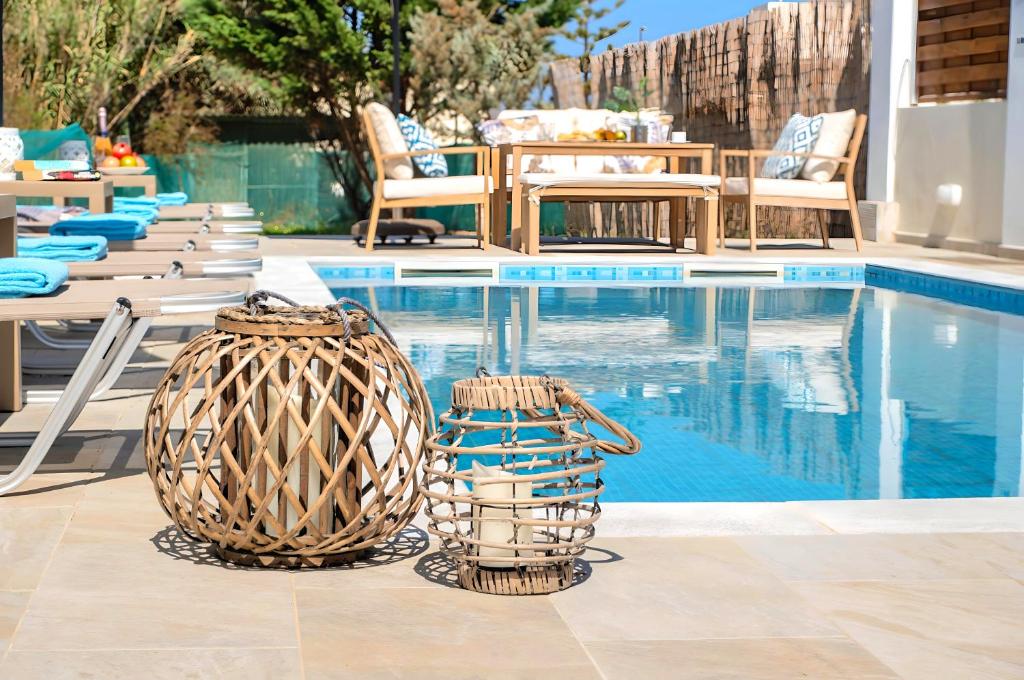 Eliomar Beachside Villa في مدينة خانيا: سلتين تجلسان بجانب حمام السباحة