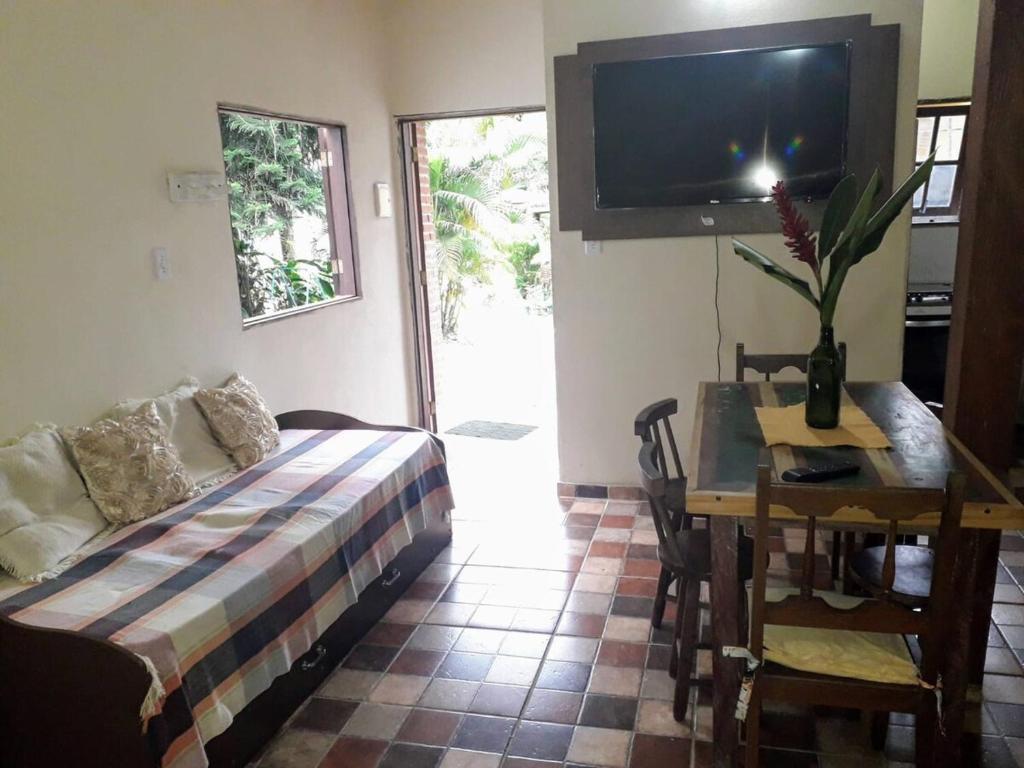 un salon avec un canapé, une table et une télévision dans l'établissement Recanto das Árvores, à Parati