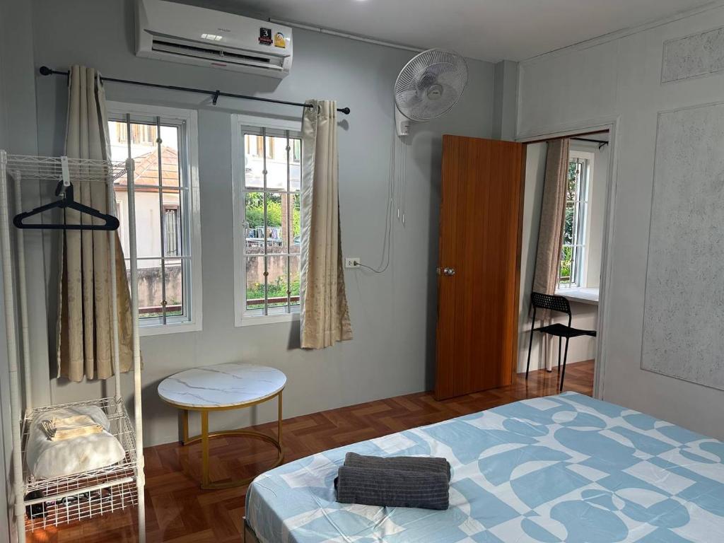 ein Schlafzimmer mit einem Bett und einem Tisch und Fenstern in der Unterkunft Mango Guest House Choeng Thale in Ban Thalat Choeng Thale