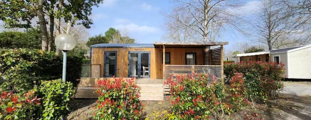 une petite maison dans un jardin fleuri dans l'établissement Mobil Home Escapade Chic et Nature au bord du Lac, à Biscarrosse