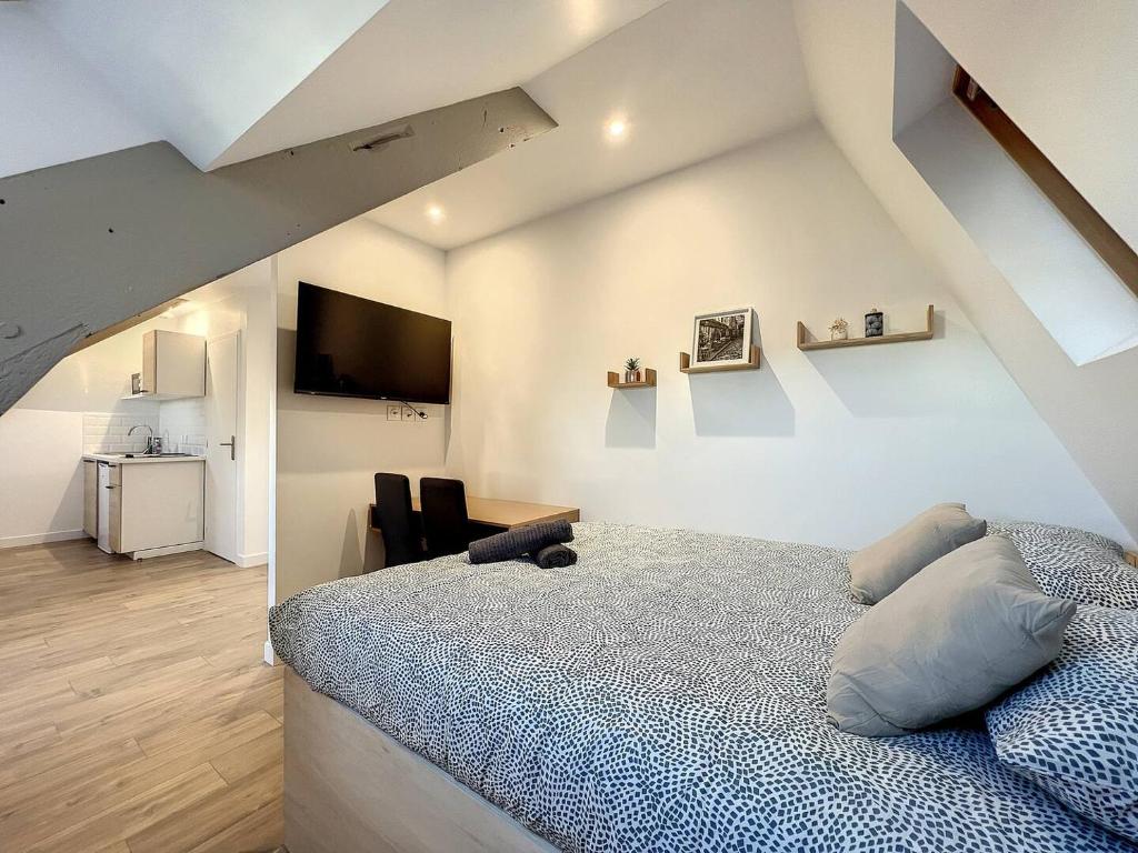 une chambre avec un lit et une télévision au mur dans l'établissement Studio sous les toits Tour d'auvergne, à Saint-Brieuc