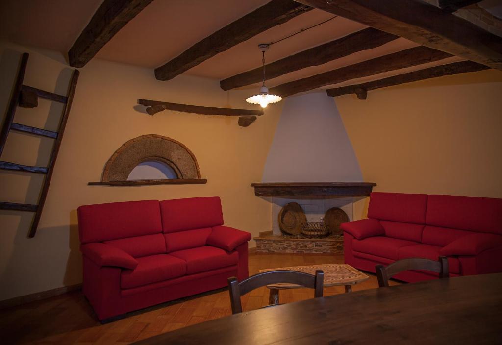 un soggiorno con 2 divani rossi e un camino di Antico Restauro a Fonni