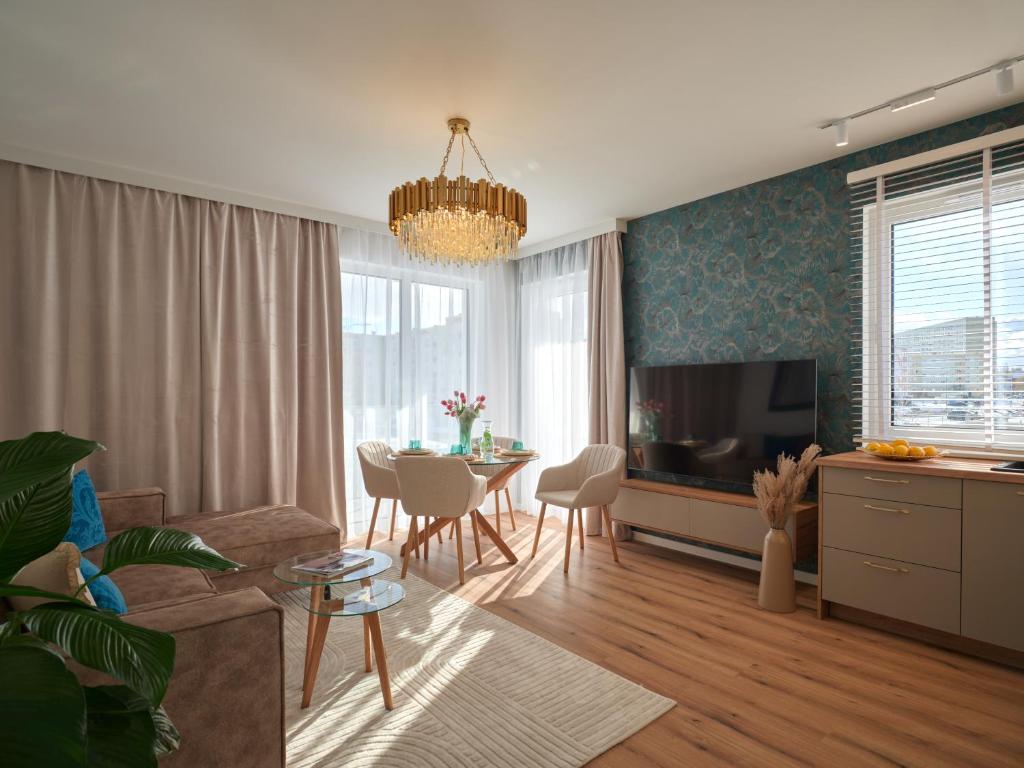 Una sala de estar con un sofá, un televisor y una mesa. en Prestige Luxury Apartament, en Koszalin