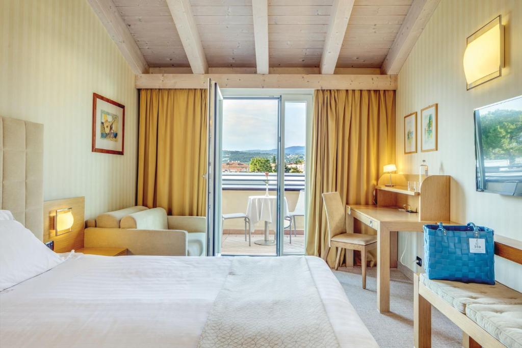een hotelkamer met een bed en een bureau met uitzicht bij Hotel Caesius Thermae & Spa Resort in Bardolino