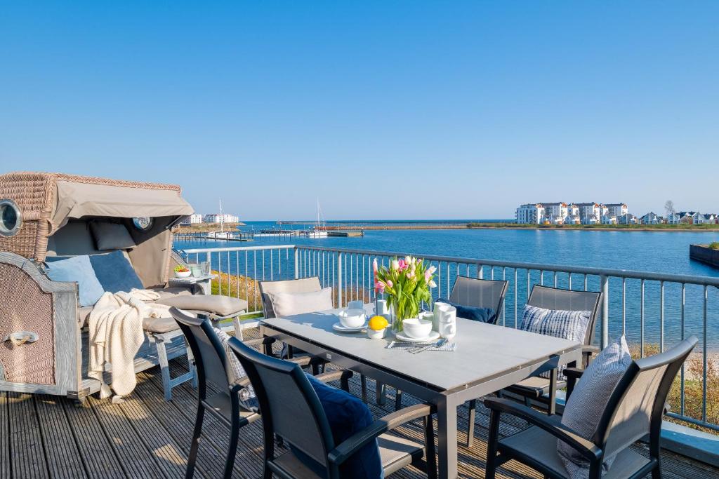 a table and chairs on a deck with a view of the water at SeaPearl- Hafenblick, Terrasse, Bad mit Infrarotsauna und Whirlwanne in Olpenitz