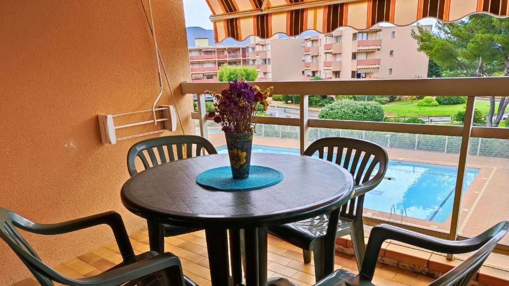 d'une table avec des chaises et un vase avec des fleurs sur le balcon. dans l'établissement Studio- Piscine- Clim- Plages, à Bormes-les-Mimosas