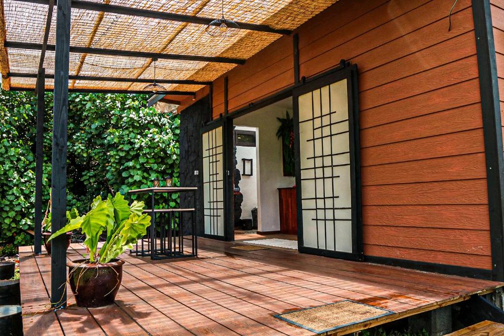 um alpendre de madeira com uma porta e um vaso de plantas em Tahaa Cosy Home em Tautu
