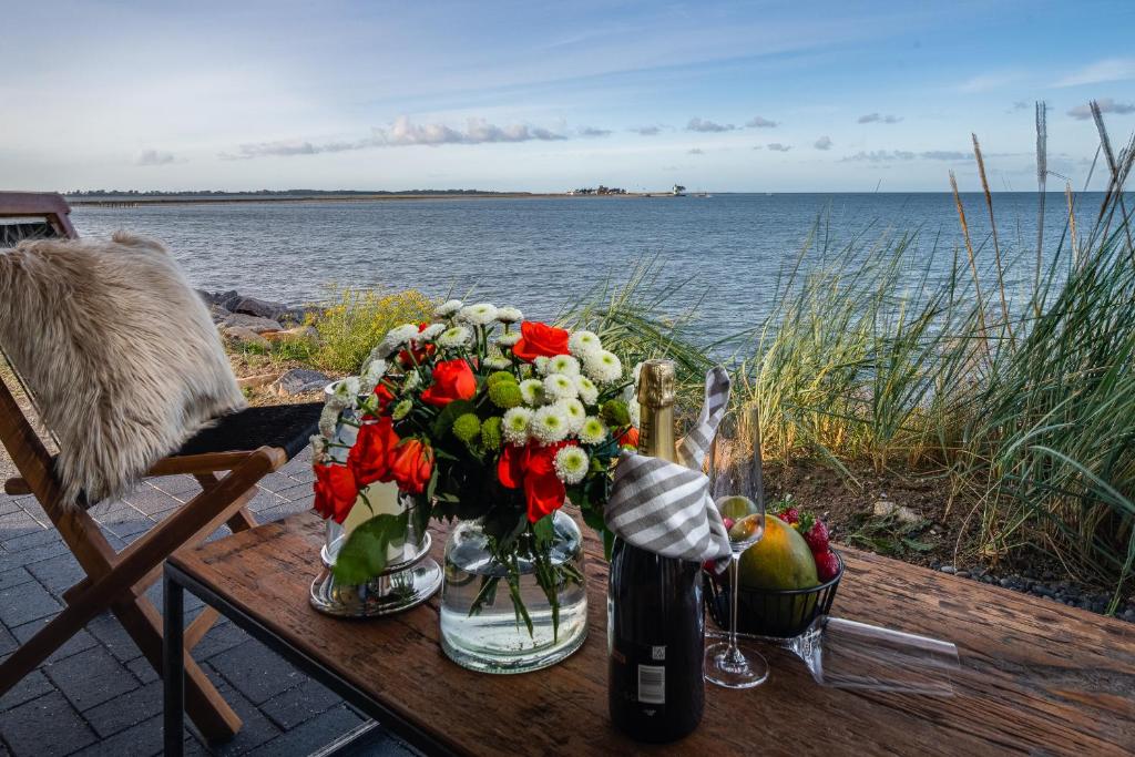 a table with a bouquet of flowers and a bottle of wine at Ferienwohnung Nordglanz – Modernes Beachhouse-Flair im Herzen des OstseeResort Olpenitz in Olpenitz