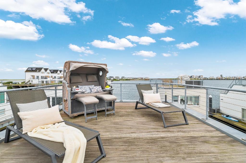 une terrasse avec des chaises et une table sur l'eau dans l'établissement Schleikubus – Ihr schwimmendes Ferienparadies im OstseeResort Olpenitz, à Olpenitz