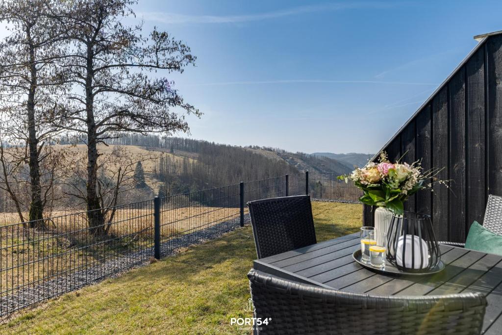 a table with a vase of flowers on a balcony at Ferienhaus Spitzenblick 2 - Sankt Andreasberg im Harz in Sankt Andreasberg