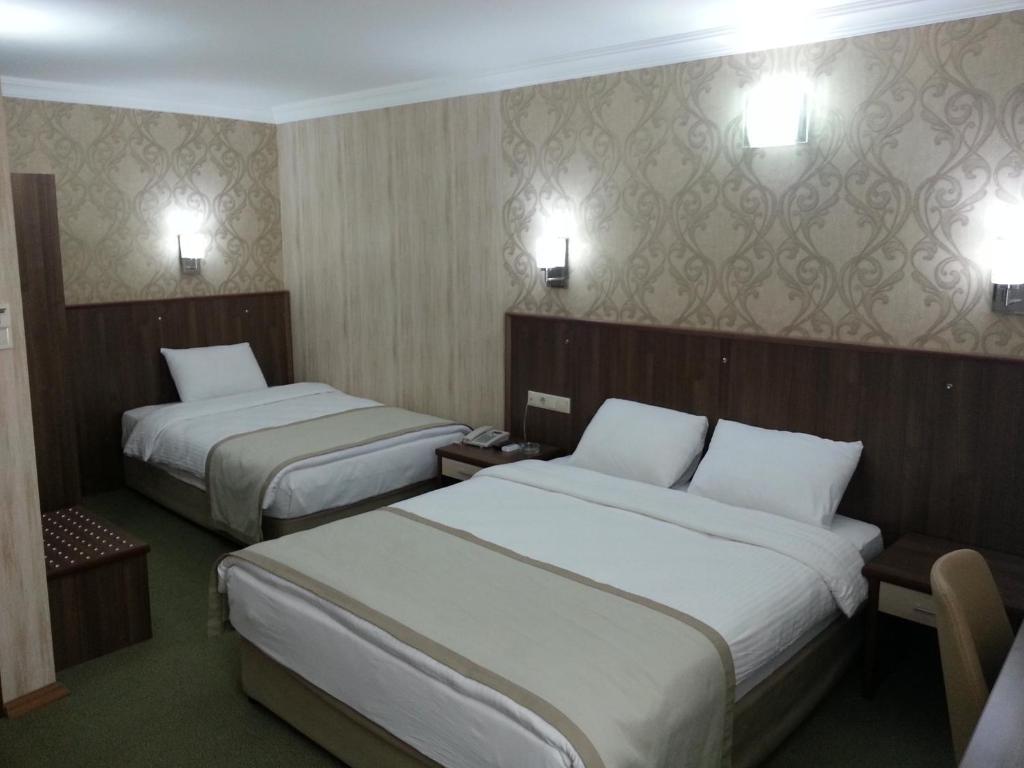 アダナにあるHosta Otelのベッド2台、壁に照明が備わるホテルルームです。