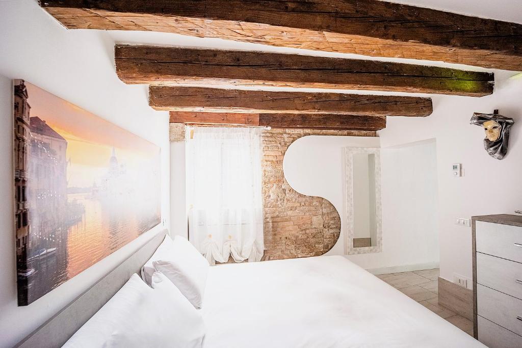 une chambre avec un lit blanc et un mur de briques dans l'établissement La Vida by Venicevillas, à Venise