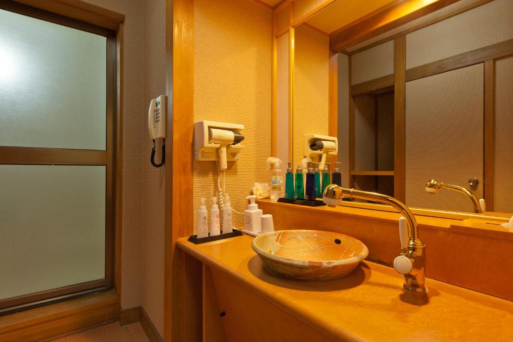ein Badezimmer mit einem Waschbecken und einem Spiegel in der Unterkunft Umibenokakureyu Seiryu in Nishiizu