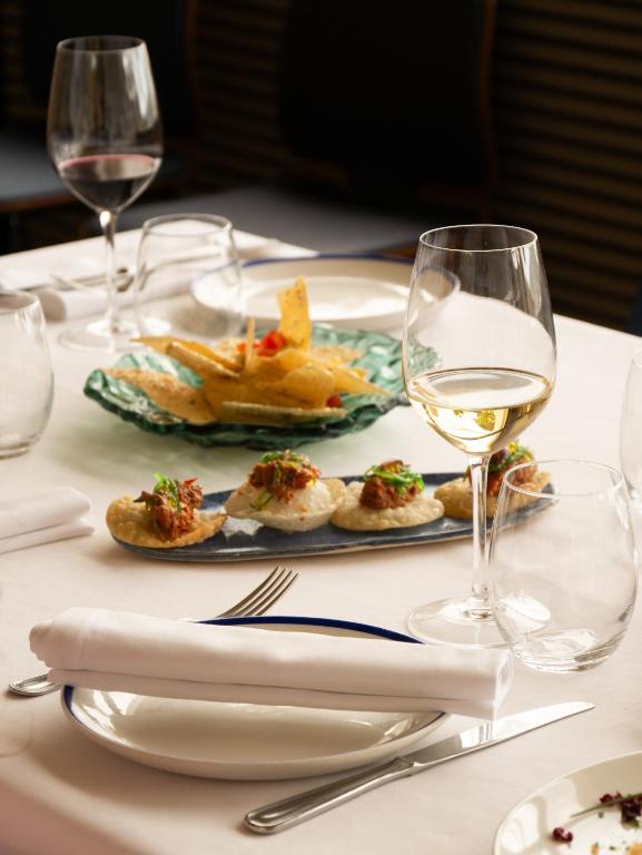 a table with a plate of food and glasses of wine at Hostal Empúries in L'Escala