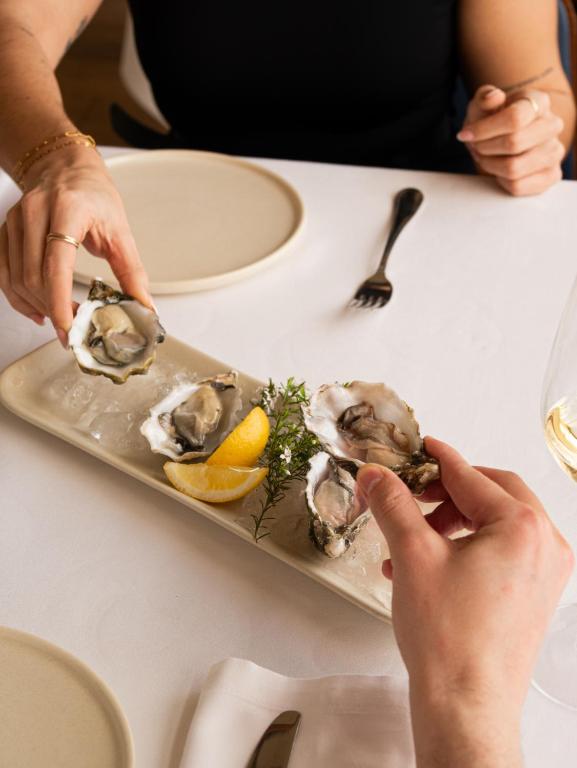 a plate of oysters with lemon on a table at Hostal Empúries in L'Escala