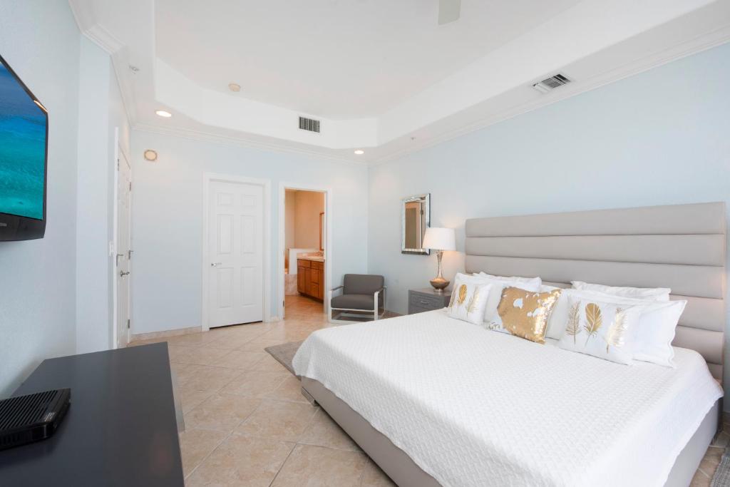 ein weißes Schlafzimmer mit einem Bett und einem Schreibtisch in der Unterkunft South Bay Beach Club #37 Penthouse - 3 Bedroom 3 Bathroom Unit in George Town
