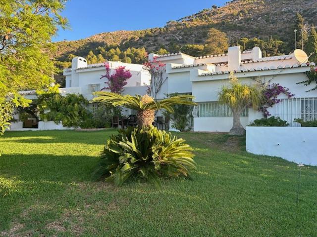 a large white house with plants in a yard at Villa Loupiro in Mijas