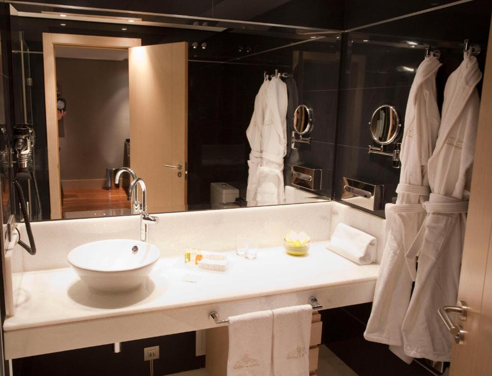 a bathroom with a sink and a large mirror at Nexus Valladolid Suites & Hotel in Valladolid