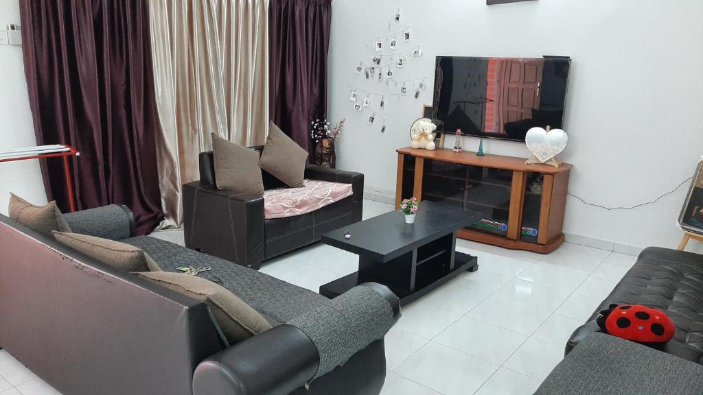 Glory Homestay Ipoh في ايبوه: غرفة معيشة مع أريكتين وتلفزيون