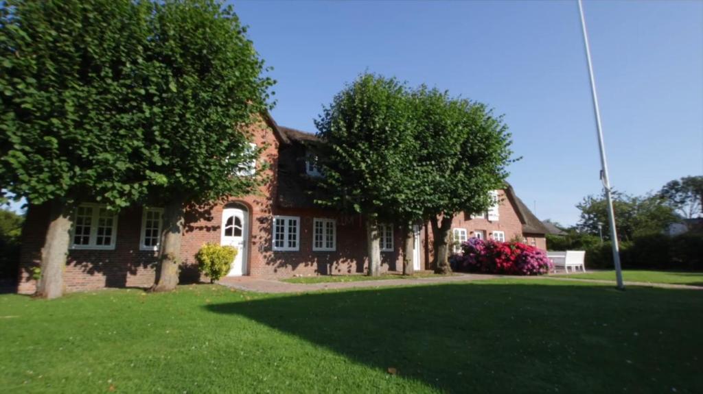 a red brick house with trees in the yard at Friesenhof Feer in Oldsum