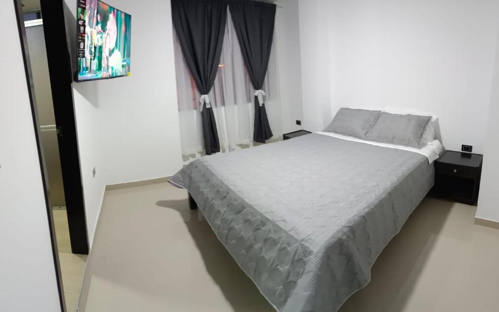 um quarto com uma cama branca e uma janela em Hotel El Redil em Ipiales