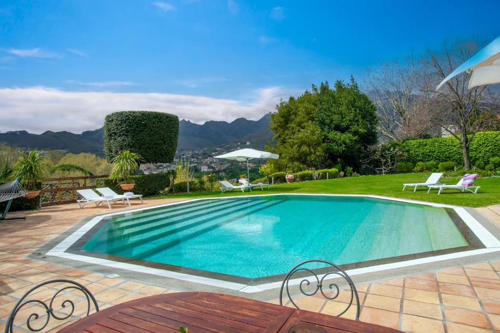 una piscina con sedie e un patio con montagne sullo sfondo di Il Piliero, a life of love a Cava deʼ Tirreni