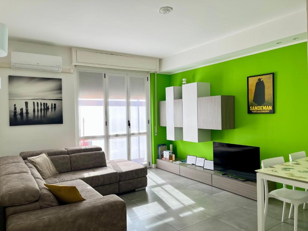 Una sala de estar con un sofá y una pared verde. en Lecco City Center Apartment, en Lecco