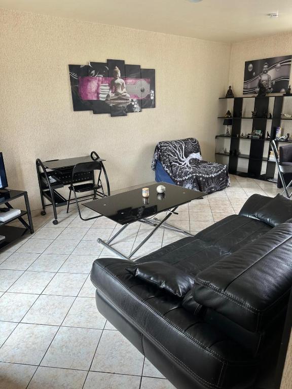 un salon avec un canapé en cuir noir et une table dans l'établissement Studio meuble coquet et zen, à Denonville